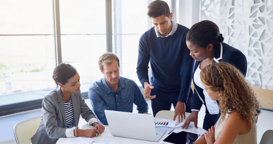 A content marketing team discussing a project around a laptop.