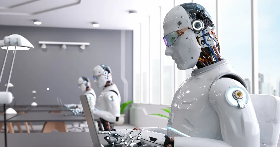An image of robots in an office typing on laptops.